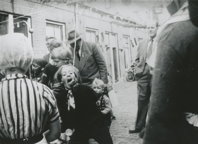  Afbeelding van het onderdeel 'koekhappen' tijdens de kinderspelen op het straatfeest in de Appelstraat te Utrecht.
